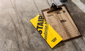 A clipboard with a paper menu featuring industrial design elements.