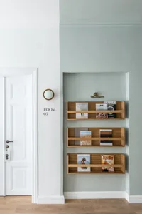 A minimalist home library featuring wooden shelves with magazines and books displayed.