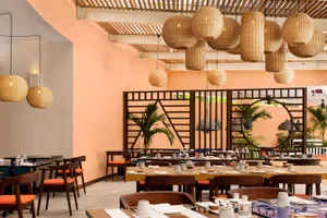 A minimalist restaurant interior with wooden furnishings and decorative lighting.
