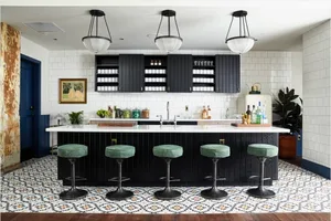 Modern kitchen with black cabinets, patterned tile flooring, and bar stools