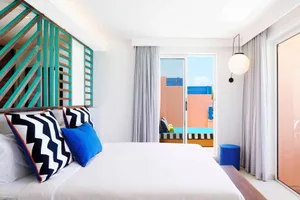 A modern bedroom featuring white textiles and a white bed.