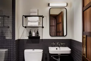A modern bathroom with dark grey tiled walls, a white toilet, and a white sink.