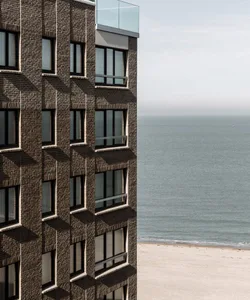 Modern building made of brick with a glass balcony overlooking the ocean.