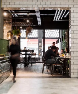 Interior of a modern cafe with metal chairs, glass tabletops, and industrial decor