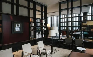 Modern hotel lobby with minimalist design featuring white chairs, floor lamps, and bookshelves.