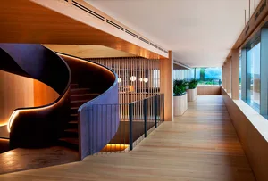 Interior view of a modern house showing a wooden corridor with a spiral staircase.