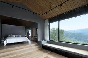 A modern living room featuring a wooden floor, large windows, a minimalist design, and a view of mountains and trees.