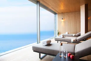 A modern minimalist relaxation area featuring comfortable lounge beds overlooking the ocean.