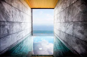 A modern minimalist swimming pool on a concrete terrace overlooking the ocean with marble accents.