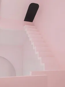 Modern architectural staircase made of pink plaster with a black wall feature.