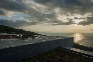 Modern rooftop deck overlooking the ocean with contemporary furniture and a green roof.