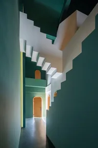 A modern staircase with white railings and green walls.
