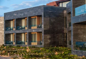Modern hotel suite with stone exterior and glass windows and balconies.