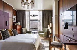 A modern bedroom with wood paneling, gray curtains, and a white bed.