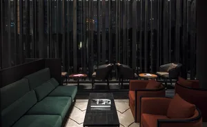 Interior design of a modern hotel lounge featuring black accent furniture, green velvet seating, and metal tables.
