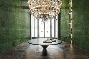 Modern lounge area with a green glass table and a large hanging chandelier.