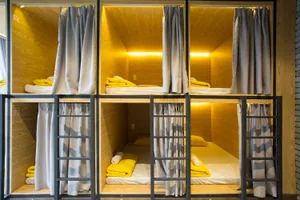 Striped bunk beds with yellow pillows and blankets in a modern bedroom with wood walls and floors.