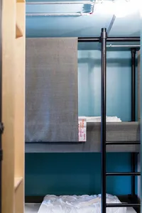 Industrial-style bunk bed with a gray curtain for privacy in a lodging room