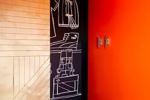 A close-up image of a door with a red wall, showcasing the texture and design of the wooden door and the vibrant orange wall.