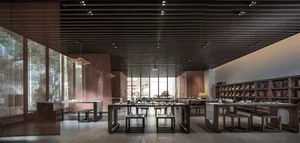 Modern minimalist tea room with wooden furniture and large windows showcasing outdoor scenery.
