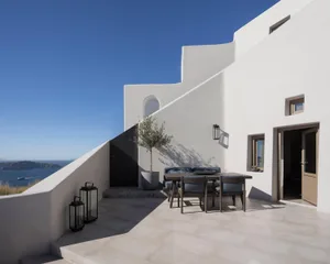 A minimalist white stucco exterior building with a small table and chairs on a terrace.