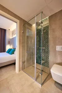 Modern bathroom interior featuring a glass shower enclosure with a geometric pattern on the tile wall.