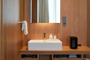 Modern bathroom with wooden walls, white countertop, and white sink.