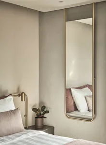 A sleek, modern bedroom featuring a mid-century mirror with a metallic frame.