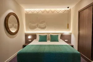 A modern bedroom featuring a textured bed and geometric wall design.