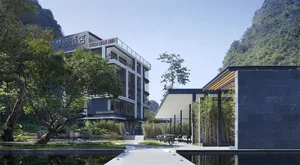 Modern hotel with concrete and glass exterior surrounded by lush greenery.