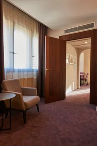 A modern hotel suite featuring wooden furnishings and a large window.