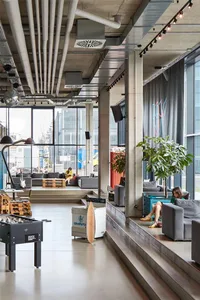 Modern, industrial-style office space featuring concrete floors, glass partitions, and minimalist furniture.
