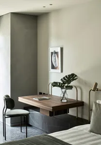 A modern living room featuring a wooden table with marble legs and a vase with monstera leaves.