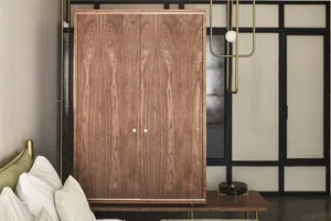 A modern wooden cabinet with two doors and metallic accents, illuminated by pendant lights.