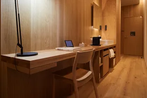 A modern, minimalist wooden workstation with a sleek desk, chair, and lighting.