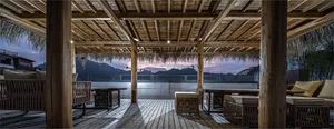 Vacation resort retreat terrace with wood-concrete-straw seating and scenic view of mountains and sunset.