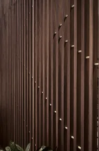 A close-up view of a wood-paneled wall with vertical slats and metallic accents.