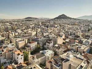雅典城市景觀的俯瞰視角，屋頂與遠處山丘映入眼簾