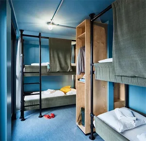 A compact industrial-style bedroom with bunk beds, metal pipes, and blue walls.