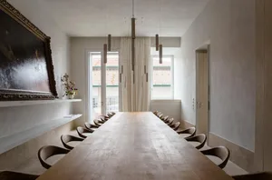 Industrial-style conference room featuring a long wooden table, modern lighting fixtures, and minimalist decor.