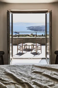 A minimalist bedroom featuring wooden furniture and a view of the sea.