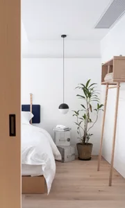 Minimalist bedroom with wooden furniture, metal accents, and potted plant.