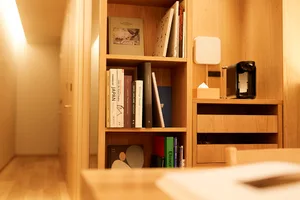 A minimalist design bookshelf constructed of wood, featuring books and a coffee maker.