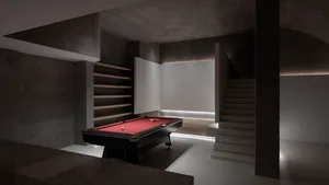 A minimalist, modern basement with a concrete floor, a red pool table, and a white wall with built-in shelves.