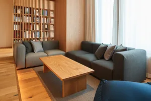 A modern living room with a gray sofa, wooden coffee table, and wooden flooring.