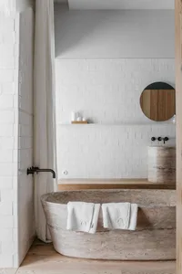 Modern bathroom featuring a marble bathtub and white subway tiles.