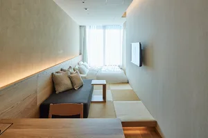 Modern minimalist bedroom with a white bed, wooden table, and minimalist design.