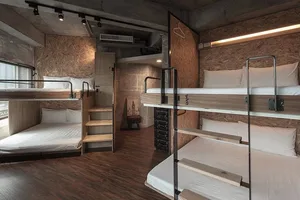 A modern minimalist bedroom with wooden bunk beds, white bedding, and a rustic ladder.