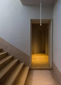 A modern staircase with concrete steps and a wooden handrail.