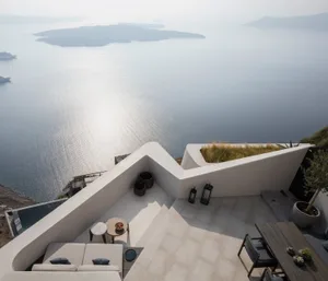 Modern minimalist terrace with concrete walls and seating area overlooking the ocean.